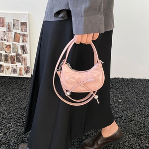 Pink patent leather dumpling bag with bow and silver beads, handheld and crossbody style