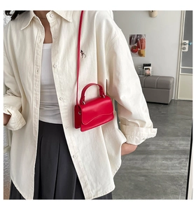 Detail of red matte leather mini bag with wavy flap and adjustable shoulder strap