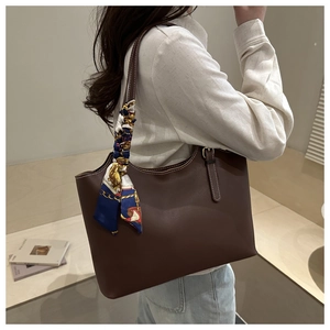 Deep brown lychee pattern tote bag with decorative scarf worn as an underarm shoulder bag