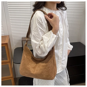 Braune Wildleder-Hobo-Tasche am Model mit verstellbarem Riemen und Goldbeschlägen