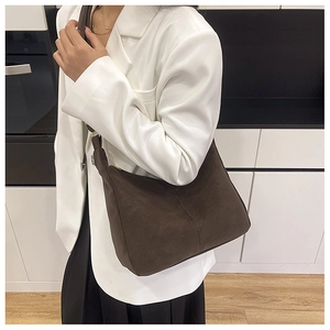 Dunkelbraune matte Umhängetasche an einem Model in moderner, eleganter Umgebung