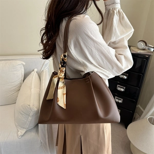 Brown pleated tote bag with decorative silk scarf accessory shown on shoulder