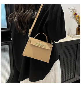 Close-up of beige trapezoid handbag featuring gold hardware and adjustable strap