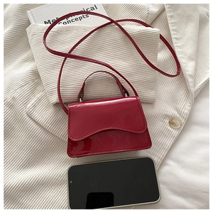 Mini borsa in pelle verniciata rossa mostrata con smartphone per dimensioni