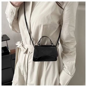 Close-up of black patent leather mini crossbody bag with a wavy curved flap design