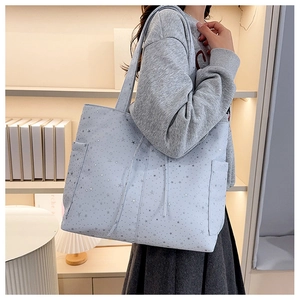 Detalle del bolso tote azul claro con estampado de estrellas y un práctico bolsillo lateral