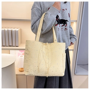 Detalle del bolso tote de lona amarilla con estampados de estrellas plateadas y bolsillos laterales
