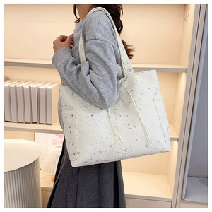 Foto lifestyle de un bolso tote de lona blanca con estrellas plateadas y bolsillos