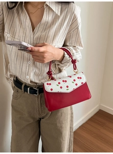 Détail du sac à main avec imprimé cerises, couleurs contrastées et anneaux dorés