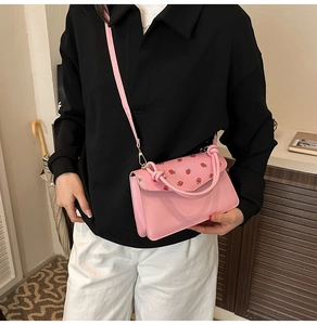Detail of pink crossbody bag featuring strawberry prints and a knotted handle design