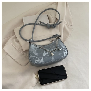 Detail of grey monogram underarm bag with silver chain and elegant pearl pendant accessory
