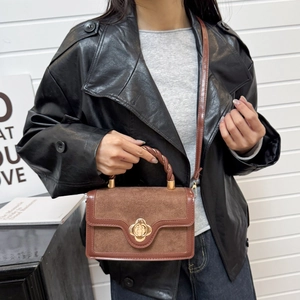 Brown frosted leather crossbody bag with floral buckle and braided handle detail