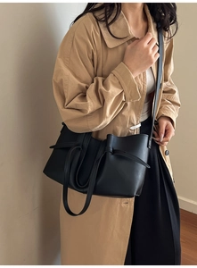 Close-up of black leather tote bag featuring stylish knot decorative straps and smooth finish