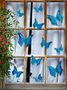 Close-up of 3D blue glowing butterfly wall stickers with glitter on glass window