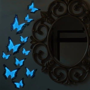 Detailed view of luminous blue butterfly wall stickers glowing in a dark room setting