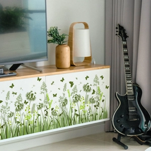 Detail of self-adhesive dandelion wall decals applied on a modern wooden TV cabinet