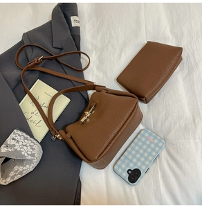 Detail of dark brown pebble leather shoulder bag with gold twist lock and matching pouch