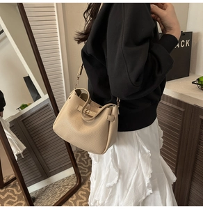 Close-up of apricot lychee pattern leather bucket bag with elegant gold twist-lock buckle