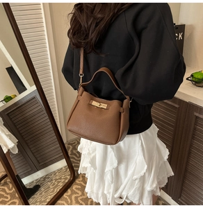 Rear view of a minimalist brown pebbled leather bucket bag styled with a shoulder strap
