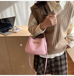 Close-up of pink litchi grain leather shoulder bag with elegant gold twist lock hardware