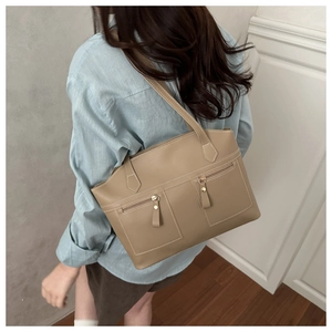 Detail of light khaki shoulder bag featuring two front zipper pockets and gold hardware