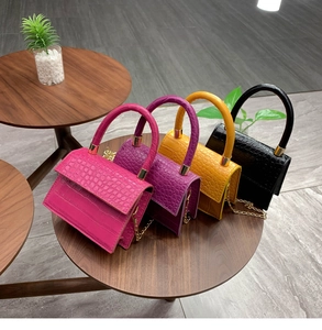 Detail of colorful crocodile texture bags with arc handles and gold chain straps
