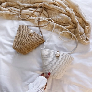 Close-up of woven straw bucket bag showing pearl closure and fine textured detail