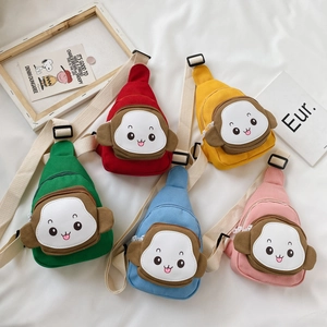 Flat lay of colorful cartoon monkey canvas crossbody bags for kids in five bright colors