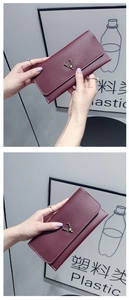 Close-up of wine red slim leather wallet with gold deer metal emblem and white stitching