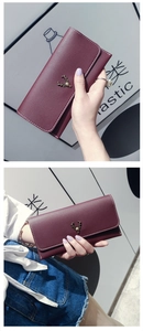 Detail of burgundy long wallet with gold deer emblem and white contrast stitching detail