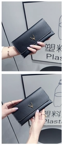 Detail of black leather long wallet featuring a gold deer logo and white stitching