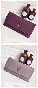 Detail of retro long wallets featuring a brass deer logo and white contrast stitching