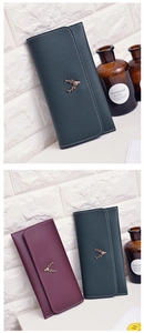 Detail of long wallets with deer emblem and contrast stitching in green and burgundy