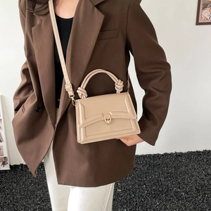 Elegant beige leather trapezoid handbag with knotted handles and gold metal clasp lock