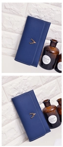 Detail of navy leather wallet featuring bronze deer head charm and white contrast stitching