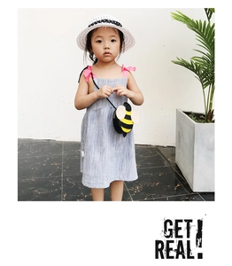 Detail of child model wearing a summer striped dress with a round bee crossbody bag