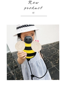 Detail shot of cute cartoon bee crossbody bag worn by a girl with black braided strap