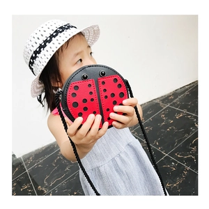 Toddler girl wearing a cute red ladybug crossbody bag with black polka dots and rope strap