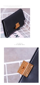 Close-up of matte black long wallet with textured gold metal buckle and neat stitching