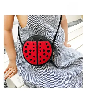 Kid's ladybug crossbody bag with red and black polka dots on a blue striped dress