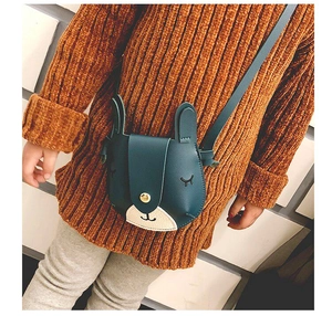 Detail showing a cute dark green rabbit-shaped crossbody bag worn on a brown sweater