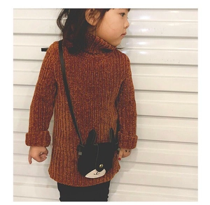Detail of a black cartoon rabbit shoulder bag with long ears on a brown knit sweater