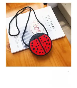 Detail of red ladybug mini crossbody bag for kids on a minimalist magazine background