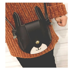 Close-up of black rabbit-shaped crossbody bag with gold snap button and leather strap
