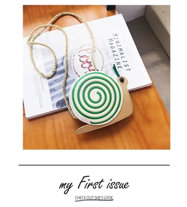 Detail view of a snail-shaped crossbody bag on a magazine featuring a green spiral shell