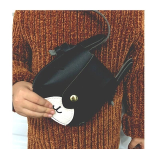 Detail of cute black animal-shaped crossbody bag with gold buckle on brown sweater