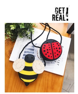 Close-up of cute ladybug and bee mini crossbody bags for kids on a wooden table