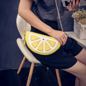 Fashionable lemon slice crossbody bag with gold chain strap worn by a model