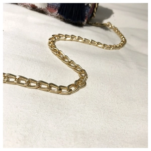 Detailansicht einer Ethno-Webtasche mit goldener Kette und farbenfrohen Quasten