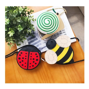 Detailed view of ladybug, bee, and snail shaped crossbody bags for children on wood
